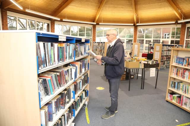 Inside view of Raunds library. An elderly man is browsing the book shelves. 