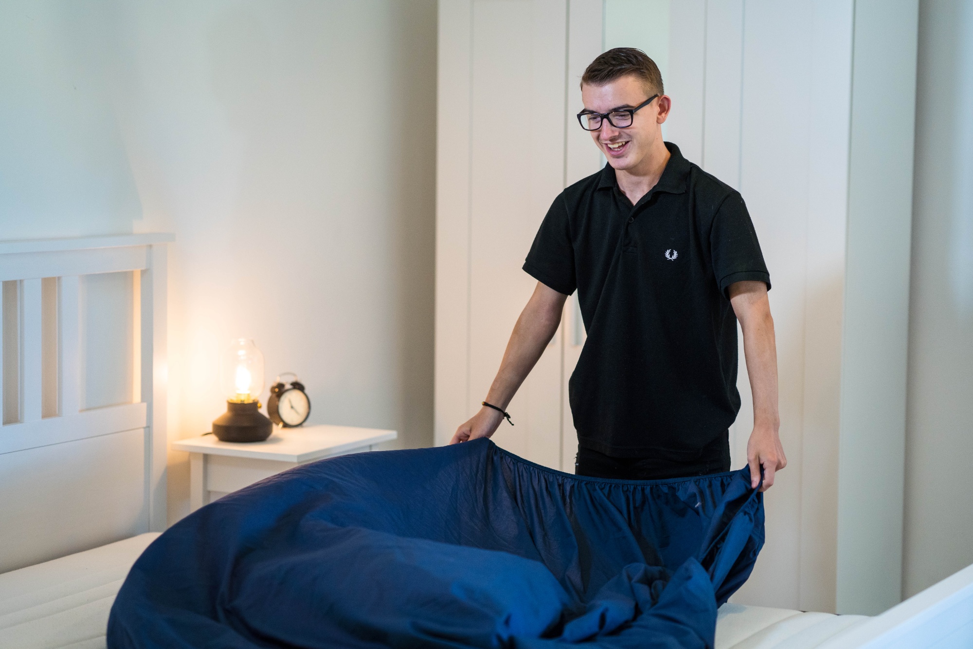 Student demonstrating independent living skills by making a bed