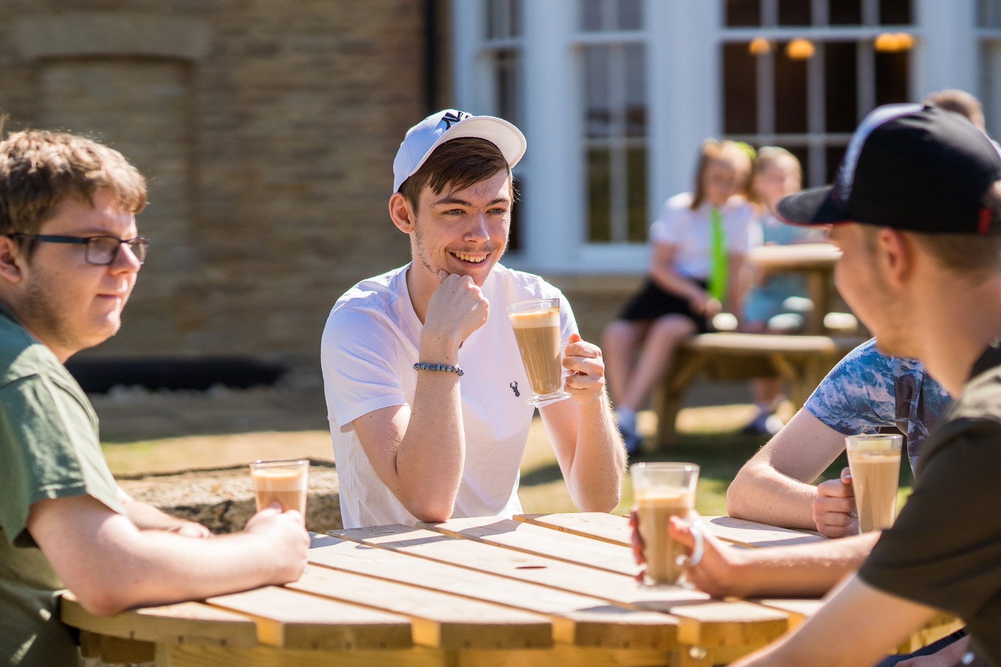 A group of students socialising over a coffee in the Court Yard at Chester House