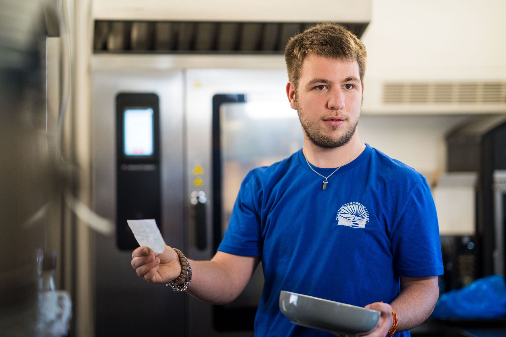 Photo of a student on a work placement in a kitchen, taking a food order.